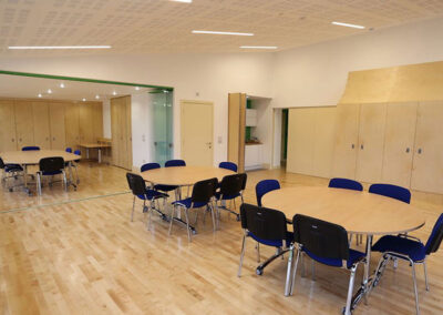 The Kier Suite - airy bright meeting space with wooden floors and plenty of wooden storage cupboards, set with 3 round tables and 6 chairs around each table